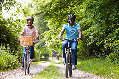 Middle Aged Couple Riding Bikes Through The Woods