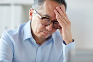 man sitting at desk with head in hand