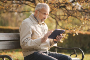 man sitting on a park bench while reading a tablet